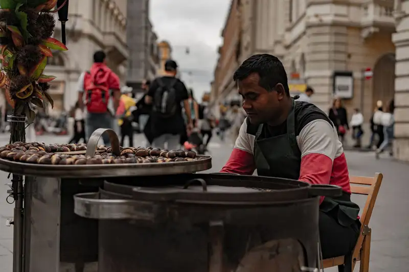 Man selling roasted chestnuts on a bustling street in Rome, Italy.