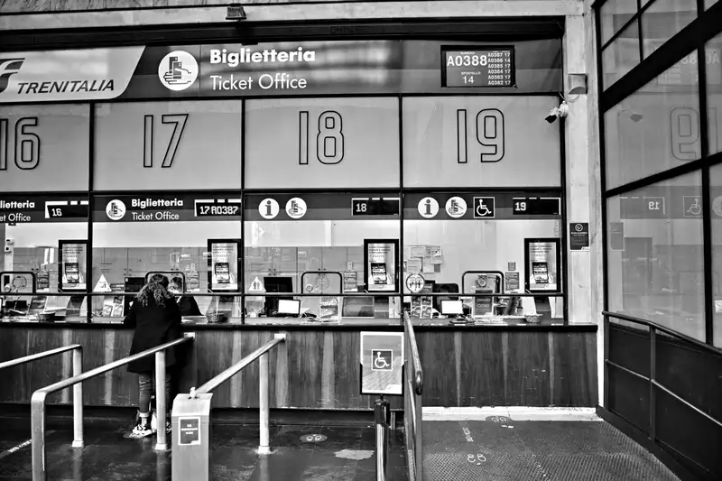Monochrome image of a train station ticket office with numbered counters, showcasing travel services.
