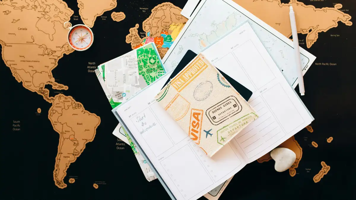 A flat lay of travel planning items on a map, featuring a compass, notebook, and guide for wanderlust enthusiasts.